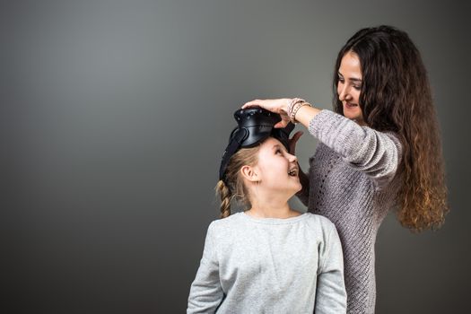 Mother and child playing together with virtual reality headsets indoors at home