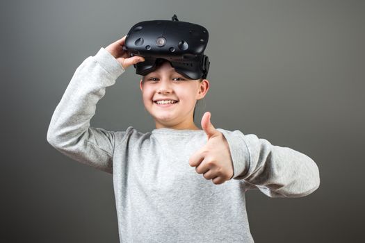 Happy little girl using a virtual reality headset show thumbs up