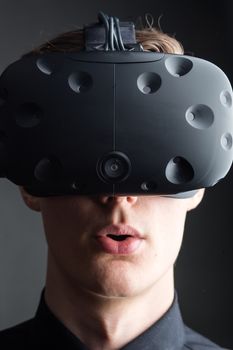 Man wearing virtual reality goggles. Studio shot, gray backgroun