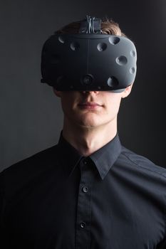 Man wearing virtual reality goggles. Studio shot, gray backgroun