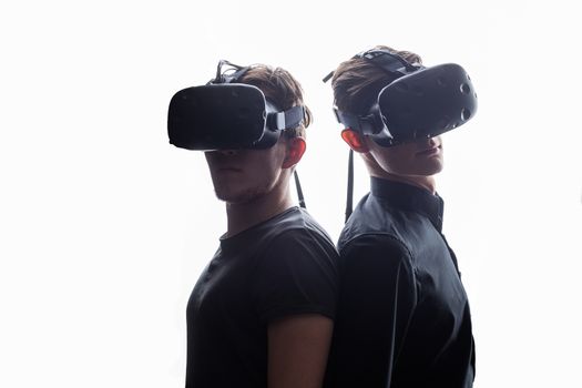 Shot of two young man standing back to back with VR goggles