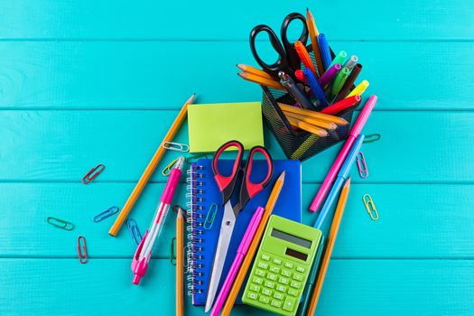 school and office supplies. school background. colored pencils, pen, pains, paper for school and student education on blue wood background. top view