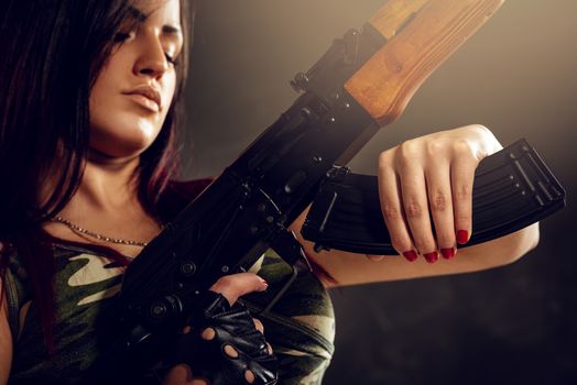 Close-up cleavage woman in camouflage shirt with an automatic rifle in her hand.