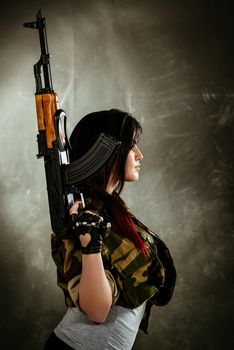 Young attractive military woman holding automatic rifle.