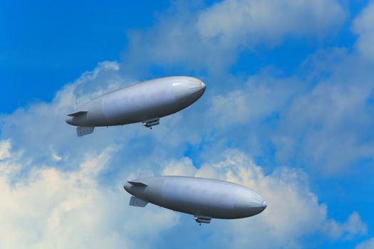 Two airships, zeppelins against blue sky with clouds.