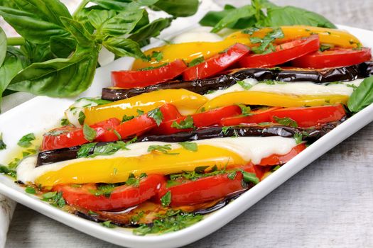 Baked eggplants with tomatoes, yellow pepper and slices  mozzarella 