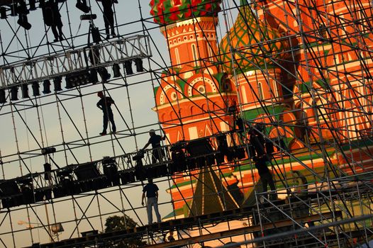 Diagonal view on workers on stage construction levels at Moscow Red Square in front of Vasiliy Blazhenniy Cathedral. Workers shadow figures on staging construction. Pop music stage under construction