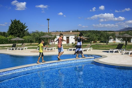 Girl and boys walking over the swimming pool
