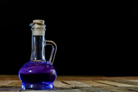 Bottles of colored liquid on a wooden kitchen table. Wooden table. Black background