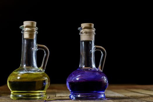 Bottles of colored liquid on a wooden kitchen table. Wooden table. Black background