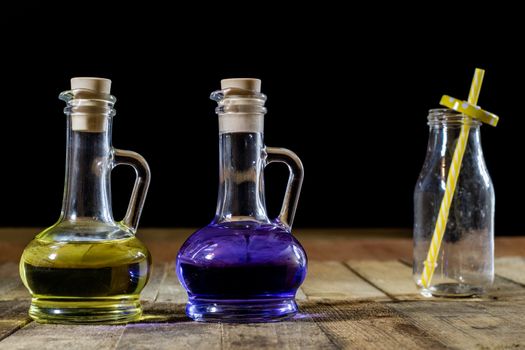 Bottles of colored liquid on a wooden kitchen table. Wooden table. Black background