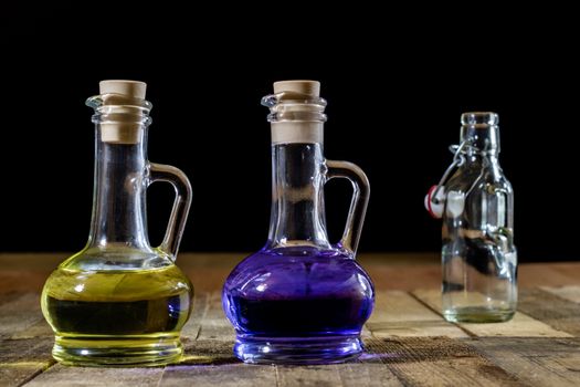 Bottles of colored liquid on a wooden kitchen table. Wooden table. Black background