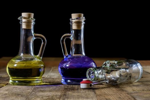 Bottles of colored liquid on a wooden kitchen table. Wooden table. Black background