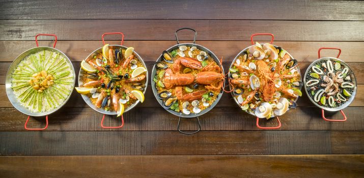 Assorted paella on wooden table, above view