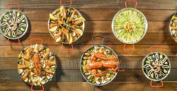 Assorted paella on wooden table, above view