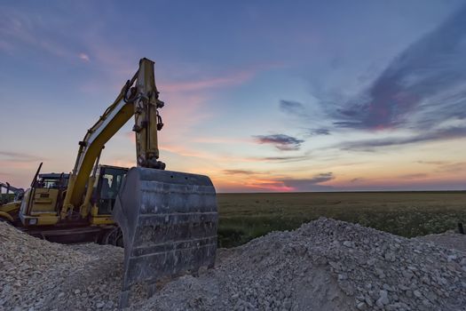 A stopping yellow excavator at an incredibly beautiful sunset