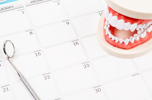 Dental appointment concept. Idea with Generic dental teeth model and dental mirror on a calendar with space for text.