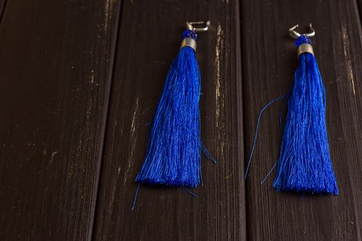 Blue thread earrings on a black wooden background