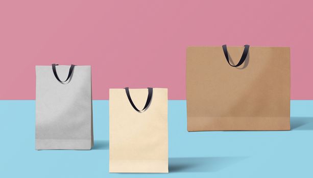 three paper bags for shopping on a pink background