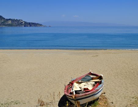 Empty sandy beach with abandoned boat in Sicily, Italy