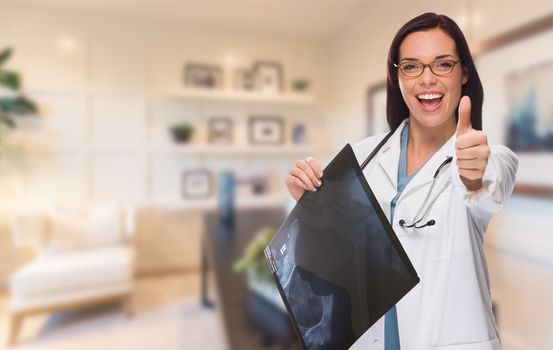 Young Female Doctor or Nurse with Thumbs Up Standing in Office Holding X-ray.