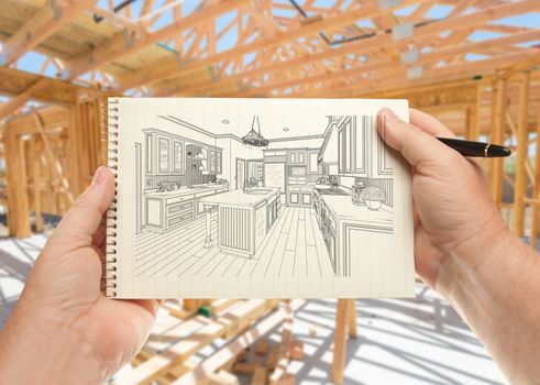 Male Hands Holding Pen and Pad of Paper with Custom Kitchen Illustration Inside Construction Framing.