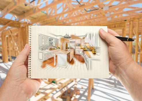 Male Hands Holding Pen and Pad of Paper with Custom Kitchen Illustration Inside Construction Framing.