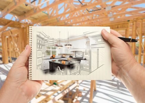 Male Hands Holding Pen and Pad of Paper with Custom Kitchen Illustration Inside Construction Framing.