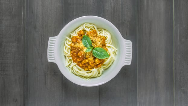 Plate of delicious spaghetti bolognese with savory minced beef and tomato sauce garnished with  basil, overhead view