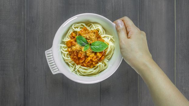 Plate of delicious spaghetti bolognese with savory minced beef and tomato sauce garnished with  basil, overhead view