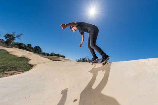 Skateboarder practice on a pump track park on a sunny summer day.