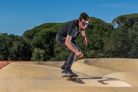 Skateboarder practice on a pump track park on a sunny summer day.