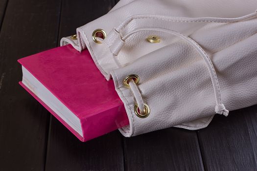 Book in female backpack closeup on the black background