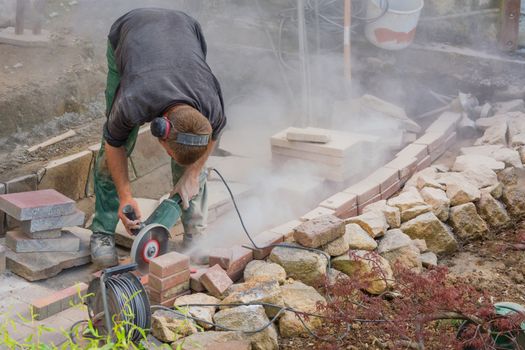 Man cutting stone slabs, concrete slab with an electric grinder