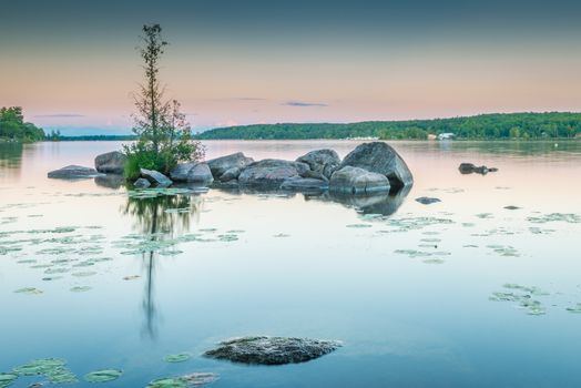 Granite rocks dot the still waters of Lower Buckhorn Lake at sunset.