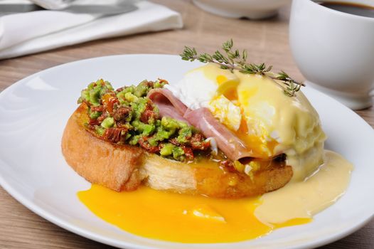 Toasted baguette slice with guacamole, ham and eggs Benedict under Dutch sauce