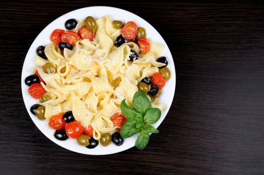 Pasta with olive, garlic, basil and tomatoes and seasoned with Parmesan cheese. Picture is a top view.
