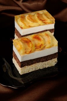 Cake stacked from caramel, apple mousse, chocolate and almond biscuit with a jelly layer of slices caramelized apple