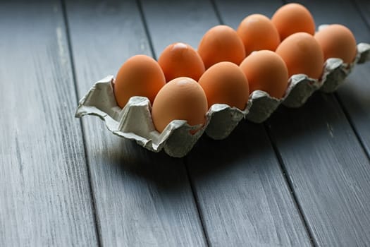 Cardboard egg box on black wooden background. Eggs container