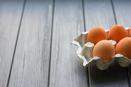 Cardboard egg box on black wooden background. Eggs container