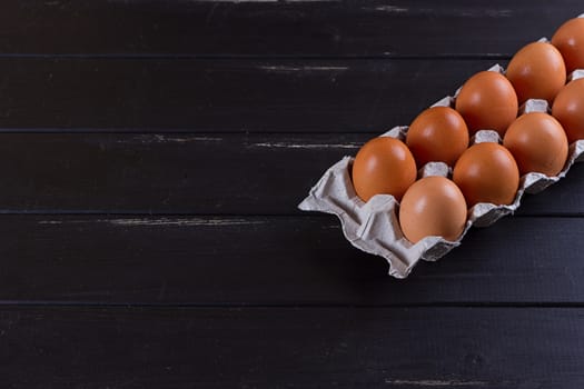 Cardboard egg box on black wooden background. Eggs container