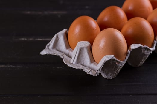 Cardboard egg box on black wooden background. Eggs container