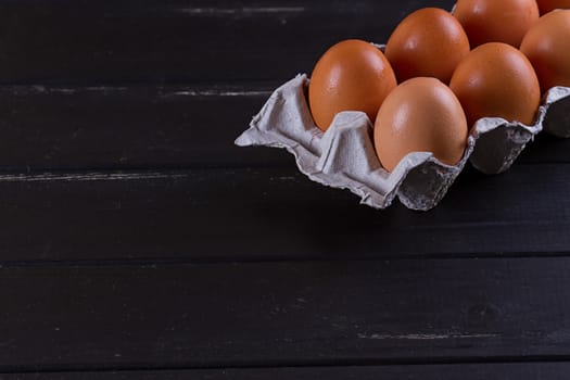 Cardboard egg box on black wooden background. Eggs container