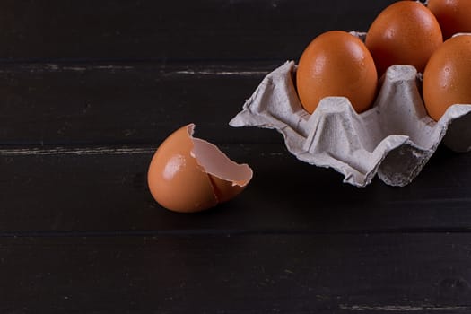 Cardboard egg box And eggshell shells on black wooden background. Eggs container