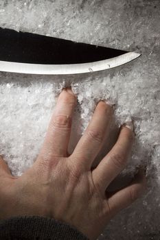 Hand of a man and a knife on white snow