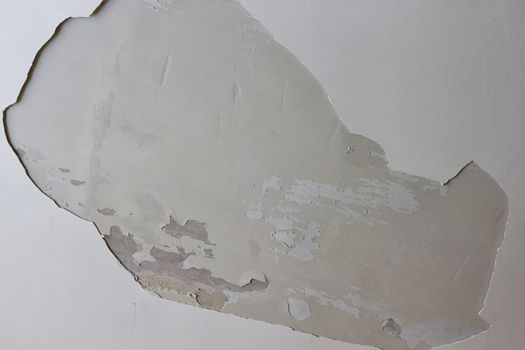 A big hole in the plastered white ceiling