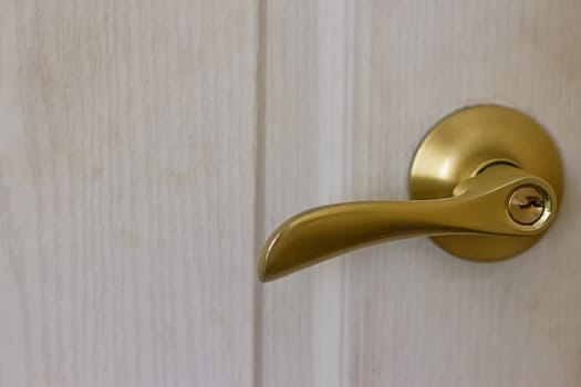 Door handle in gold on an old white door