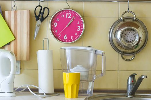 Kitchen table with water filter, clock, paper napkins