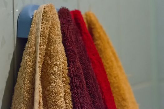 Multicolored towels hang on the hook in the bathroom home