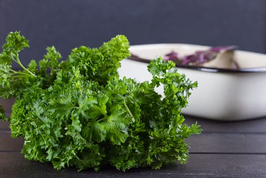 Fresh basil greens, parsley on a black background. Dark rustic style.